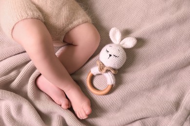 Cute newborn baby with toy bunny lying on light grey knitted plaid, top view. Space for text