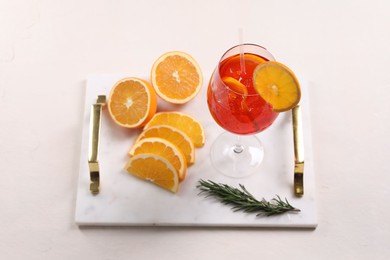 Glass of tasty Aperol spritz cocktail with orange slices and rosemary on white table, above view