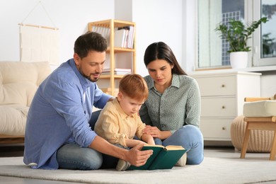 Happy family reading book together on floor in living room at home
