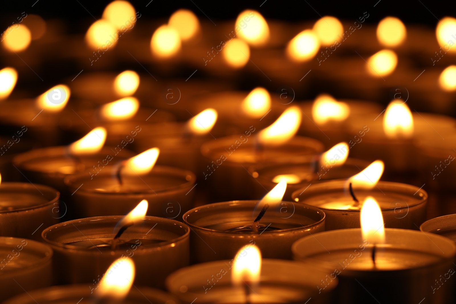 Photo of Burning candles on table in darkness, closeup