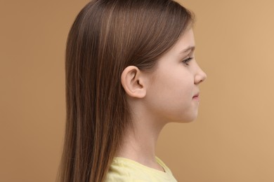 Photo of Hearing problem. Little girl on pale brown background