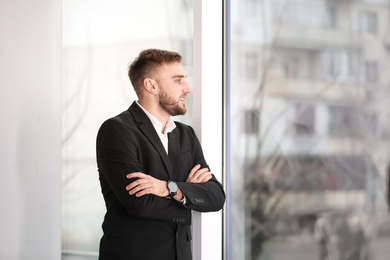 Photo of Young man in suit near window in office