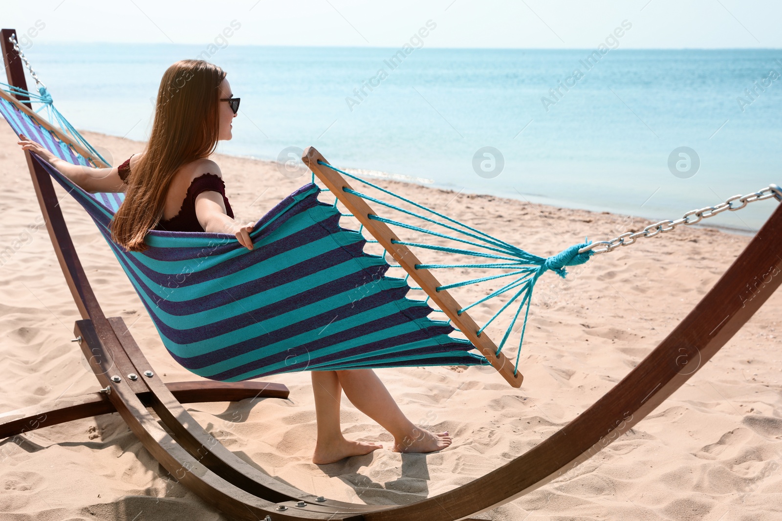 Photo of Young woman relaxing in hammock on beach