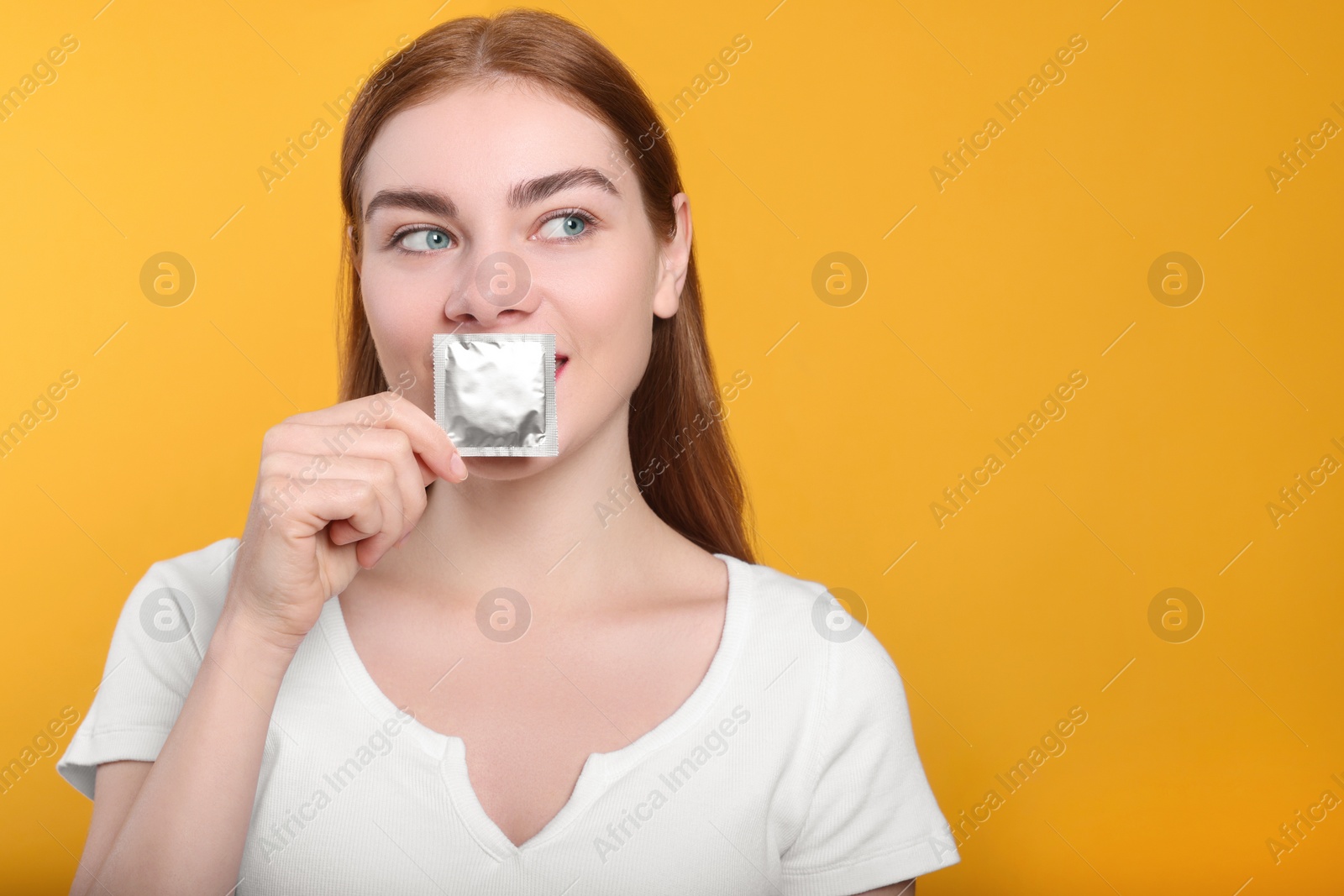 Photo of Woman holding condom on yellow background, space for text. Safe sex