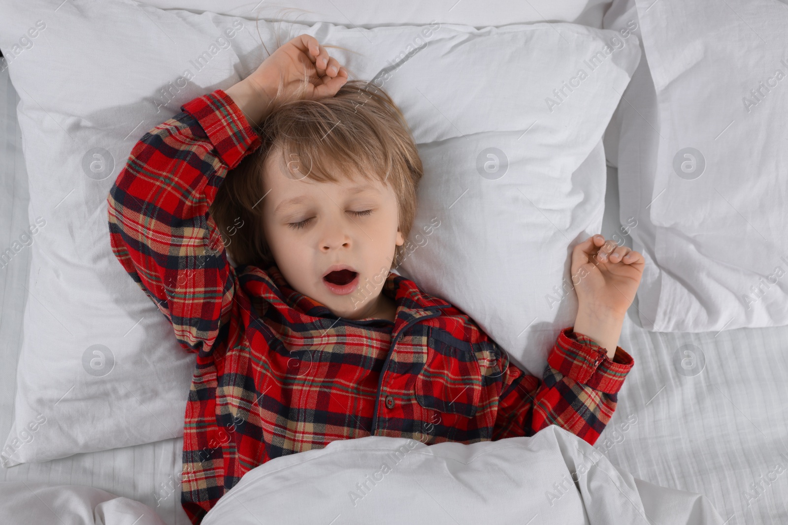 Photo of Little boy snoring while sleeping in bed, top view