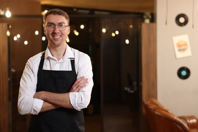 Photo of Portrait of professional hairdresser wearing apron in beauty salon, space for text