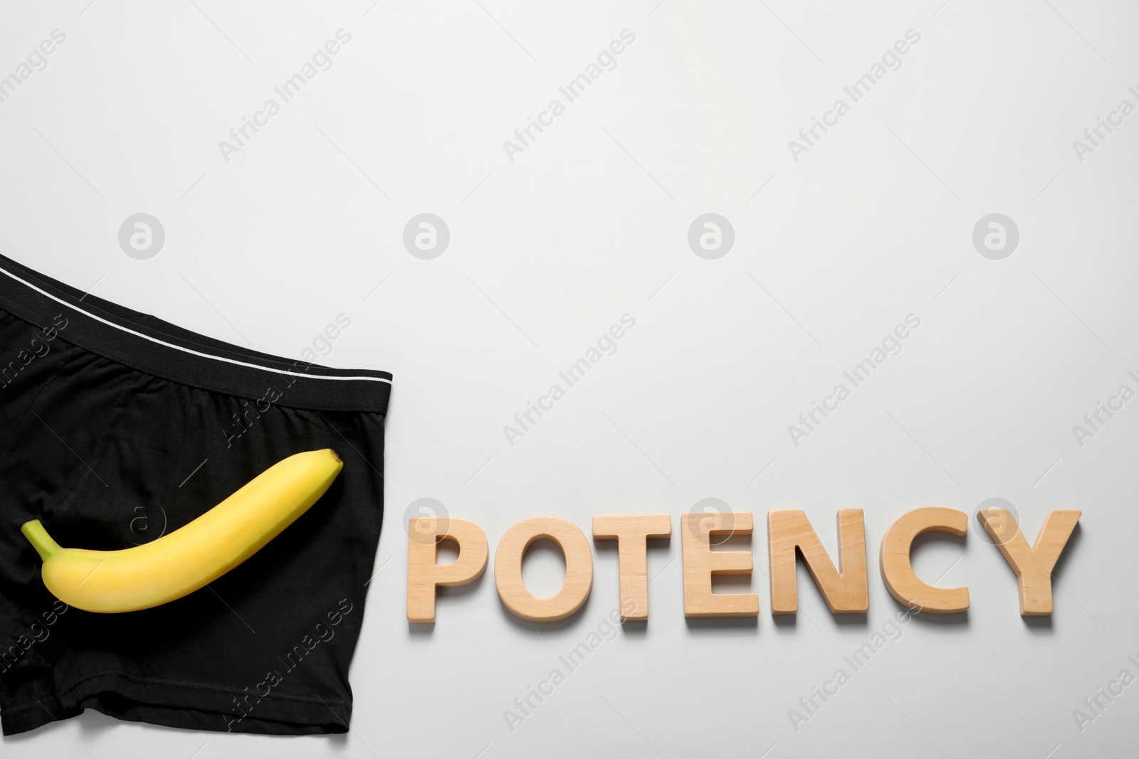 Photo of Men underwear with banana and word Potency made of wooden letters on light grey background, flat lay. Space for text