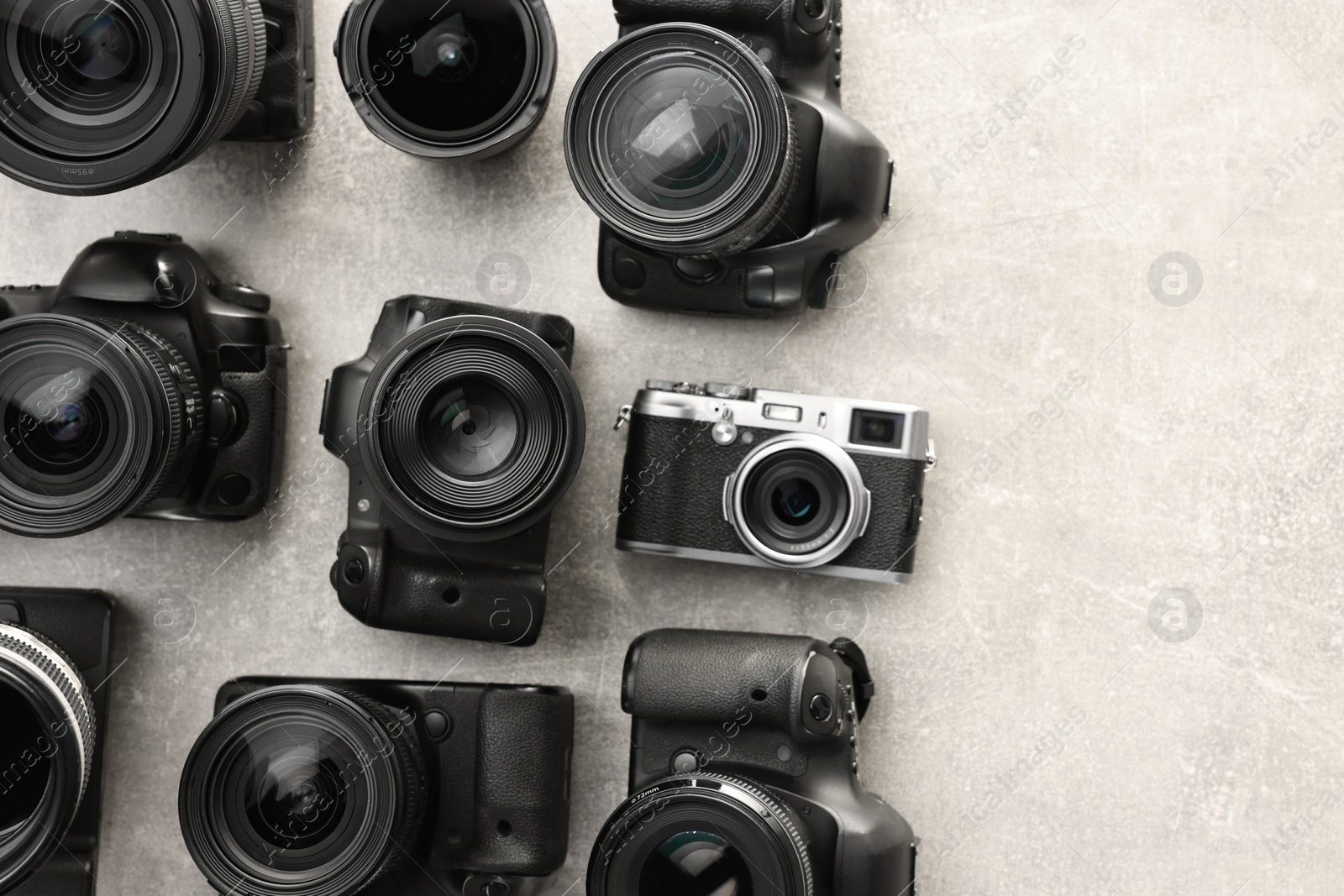 Photo of Modern cameras on gray textured table, flat lay. Space for text