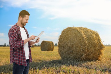 Farmer with tablet computer in field. Harvesting season