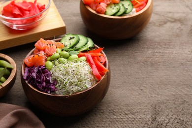Photo of Delicious poke bowls with vegetables, fish and edamame beans on wooden table, space for text