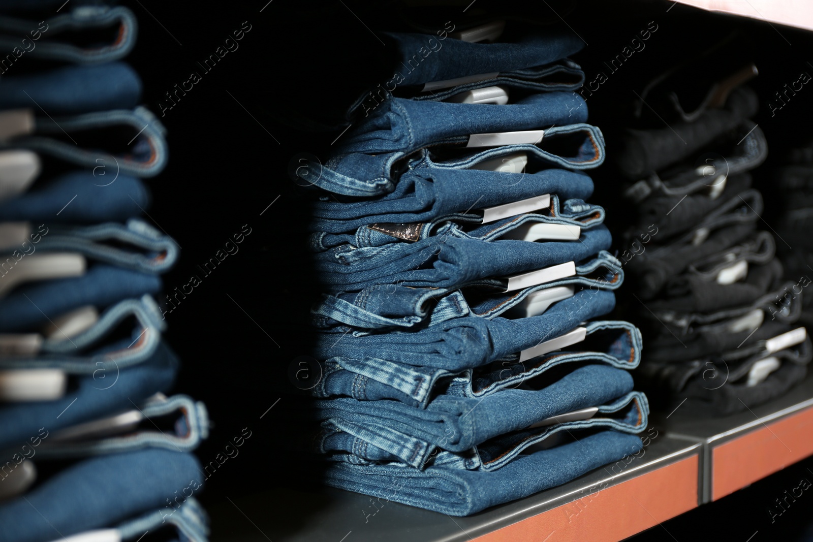 Photo of Collection of stylish jeans on shelf in shop