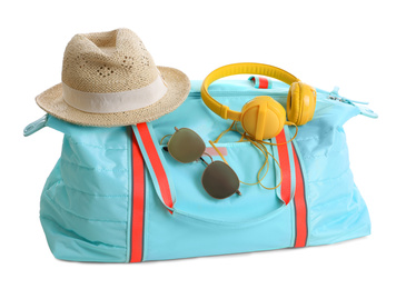 Stylish bag with sunglasses, hat and headphones on white background