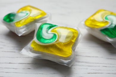 Photo of Dishwasher detergent pods on white wooden table, closeup