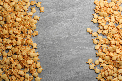 Photo of Delicious goldfish crackers on grey table, flat lay. Space for text