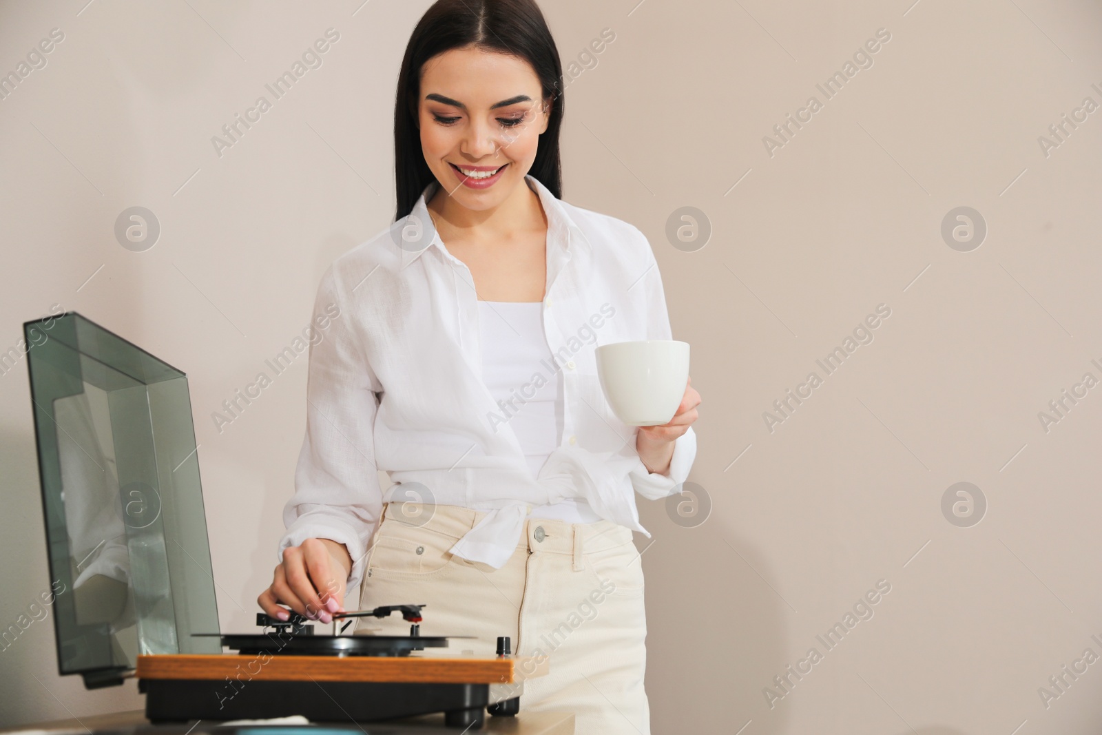 Photo of Woman using turntable on beige background. Space for text