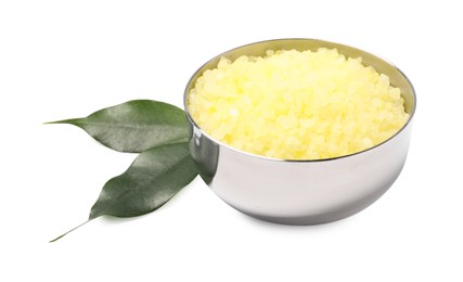 Yellow sea salt in bowl and green leaves isolated on white