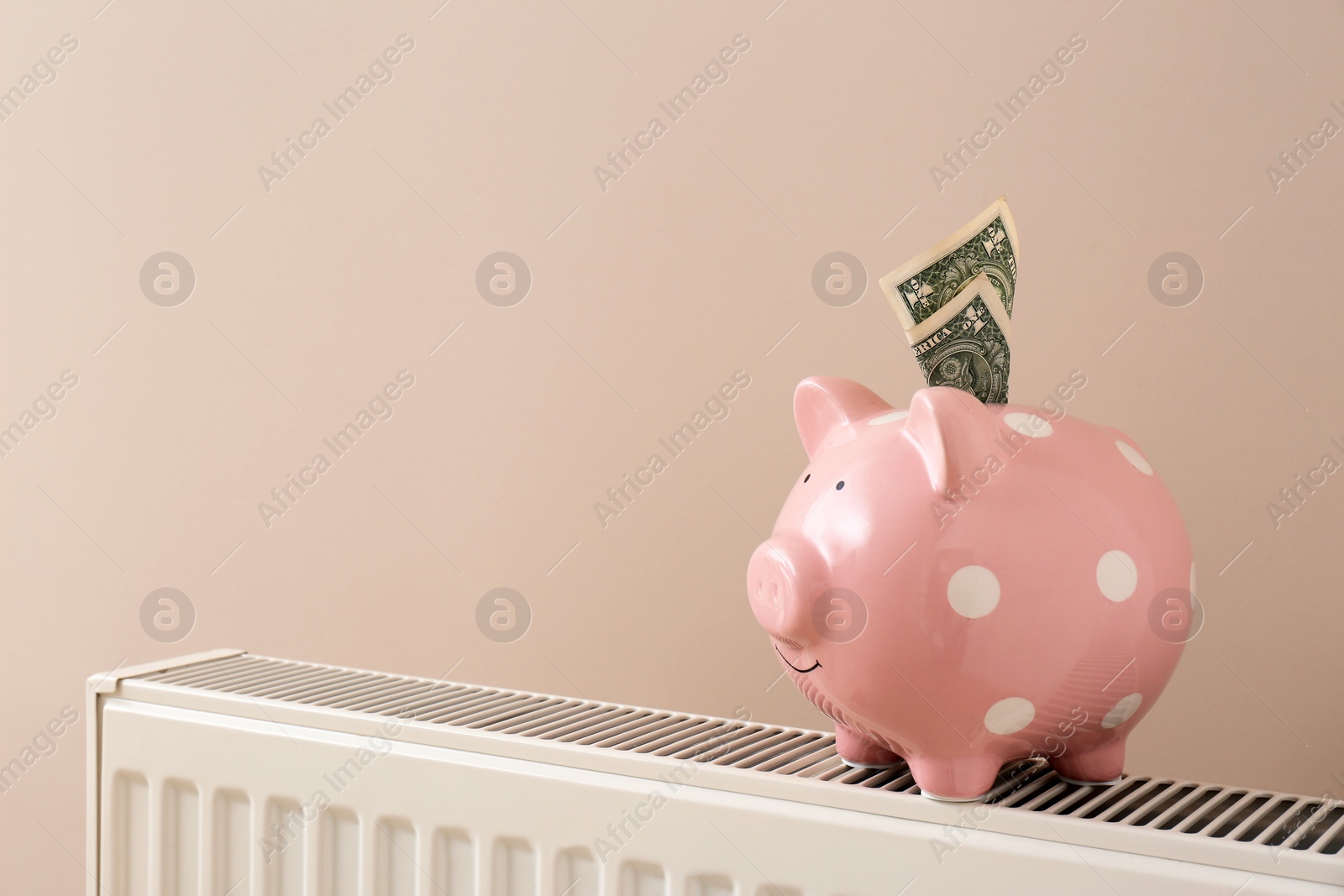 Photo of Heating radiator with piggy bank and money on color background