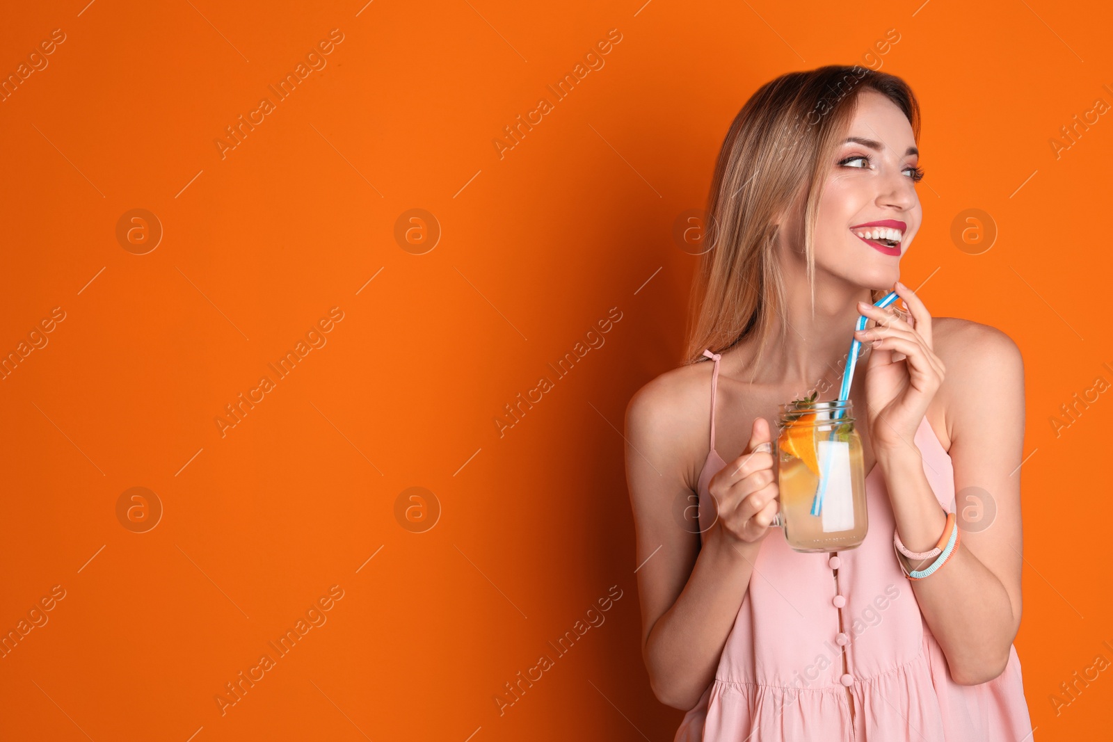 Photo of Young woman with mason jar of tasty lemonade on color background. Natural detox drink