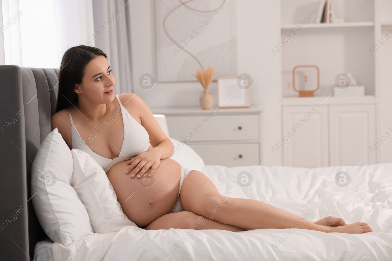 Photo of Beautiful pregnant woman in stylish comfortable underwear on bed at home