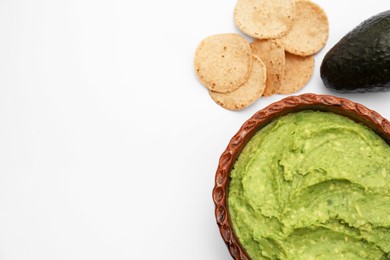 Delicious guacamole, avocado and chips on white background, flat lay. Space for text