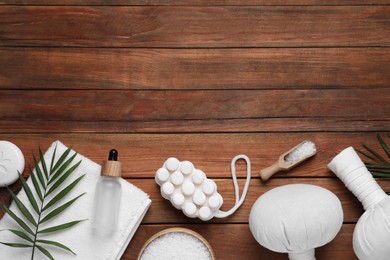 Flat lay composition of herbal bags and spa products on wooden table, space for text