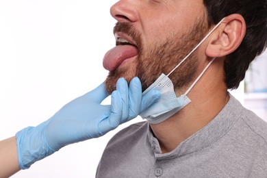 Photo of Doctor examining man`s oral cavity on white background, closeup
