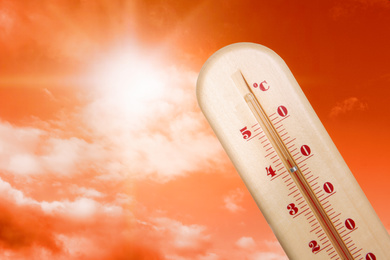 Weather thermometer with high temperature and beautiful sky toned in red on background, space for text 
