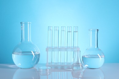 Laboratory analysis. Glass test tubes and flasks on table against light blue background