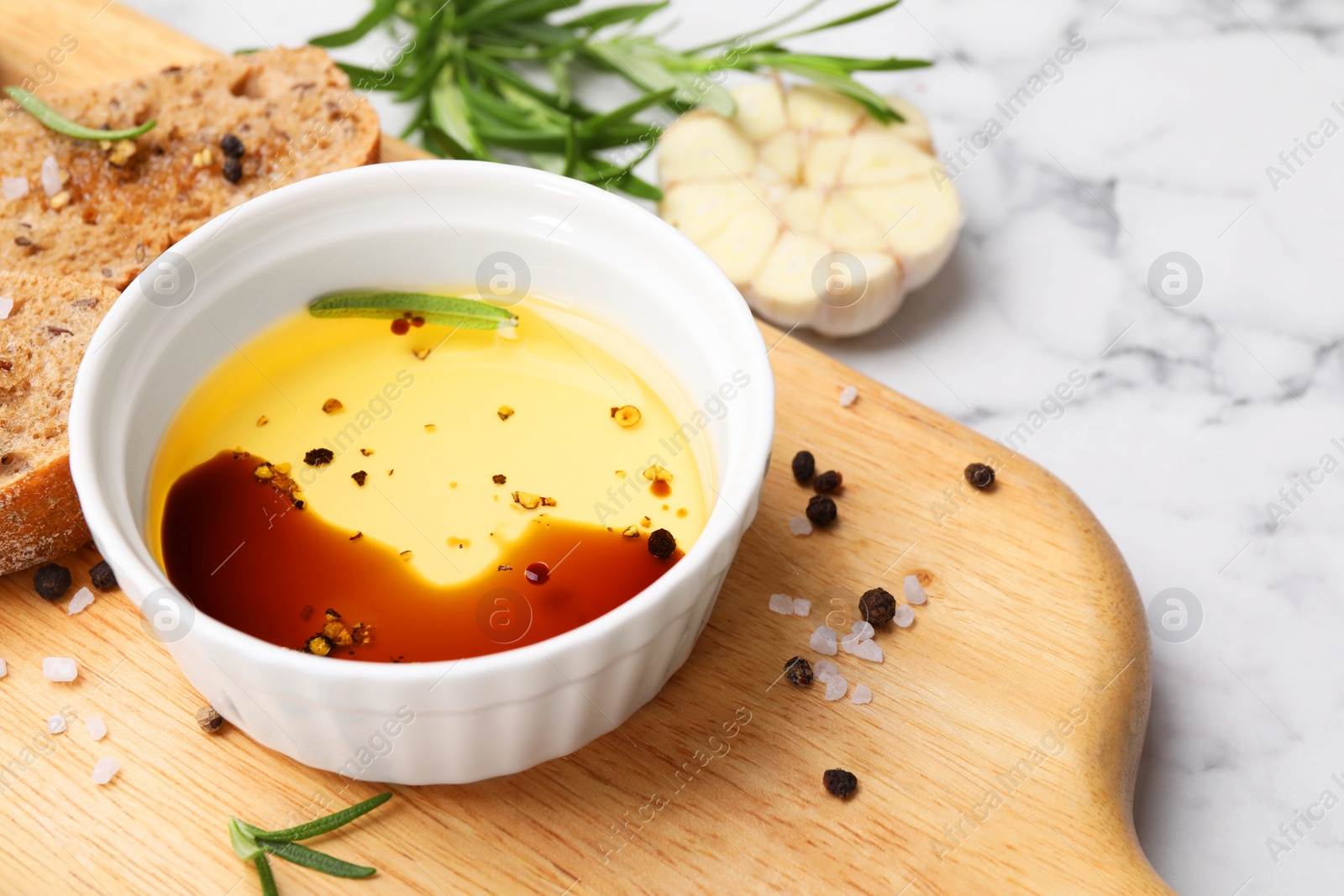 Photo of Bowl of organic balsamic vinegar with oil, bread slices and spices on white marble table, closeup. Space for text