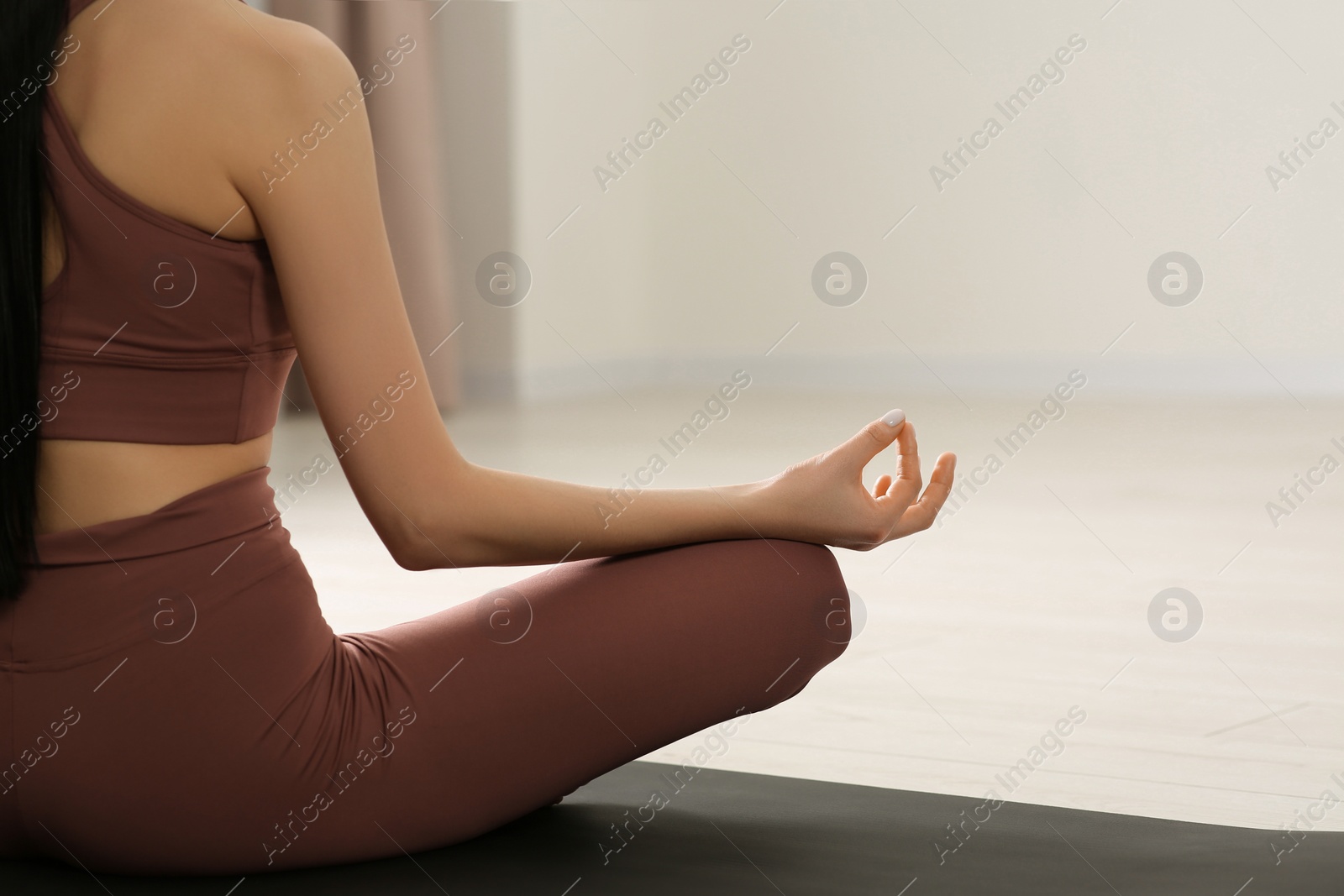 Photo of Woman in sportswear meditating indoors, closeup. Space for text