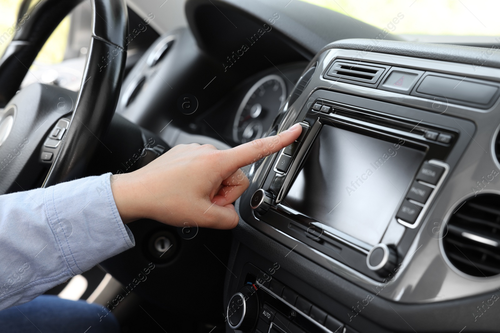 Photo of Choosing favorite radio. Woman pressing button on vehicle audio in car, closeup