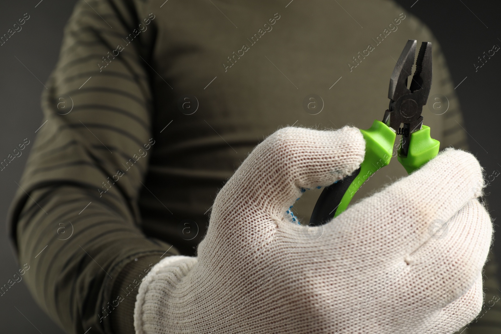 Photo of Man with combination pliers on dark background, closeup. Space for text