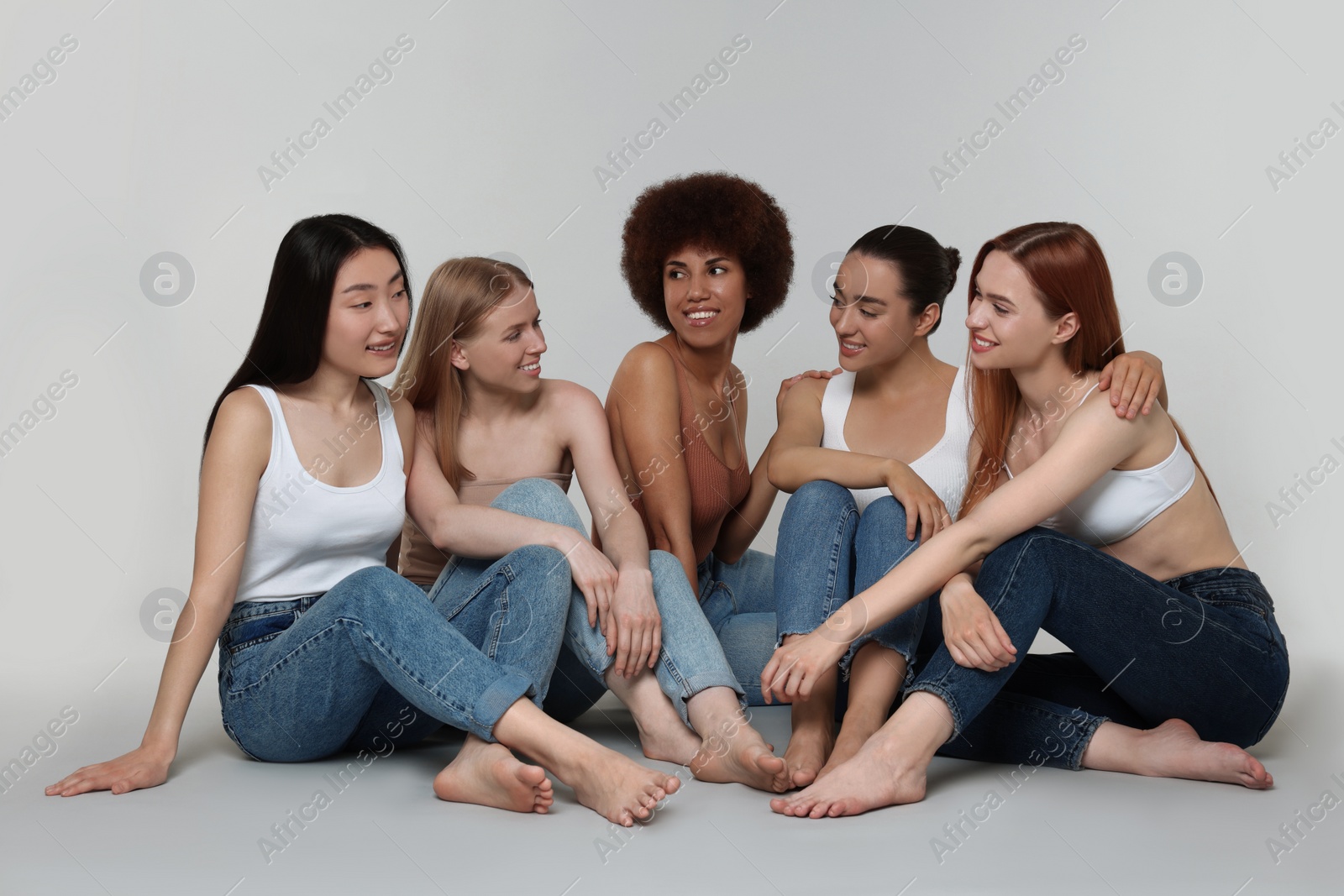 Photo of Group of beautiful young women sitting on light grey background