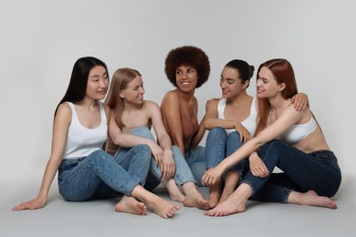 Group of beautiful young women sitting on light grey background