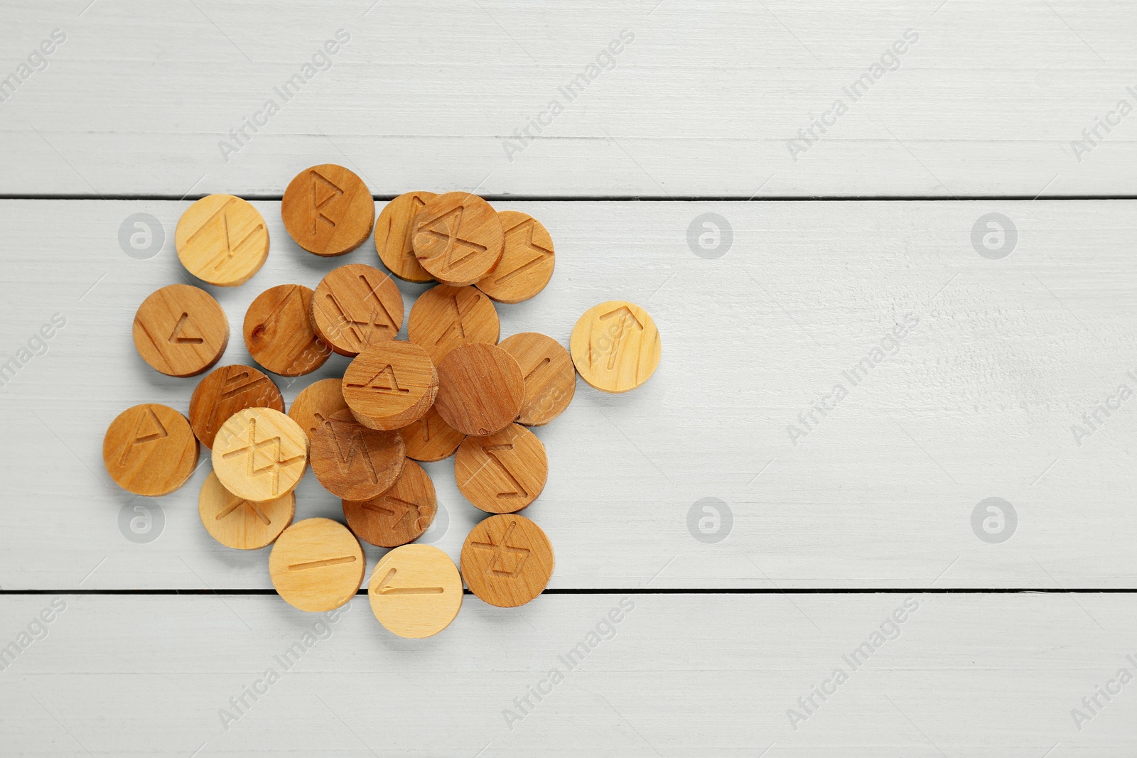 Photo of Pile of runes on white wooden table, flat lay. Space for text