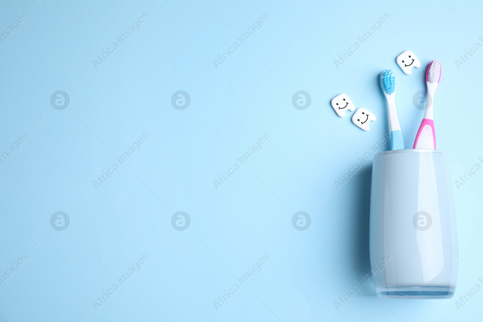 Photo of Toothbrushes in holder on light blue background, flat lay. Space for text