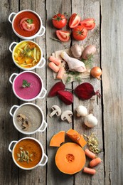 Photo of Tasty broth, different cream soups in bowls and ingredients on old wooden table, flat lay