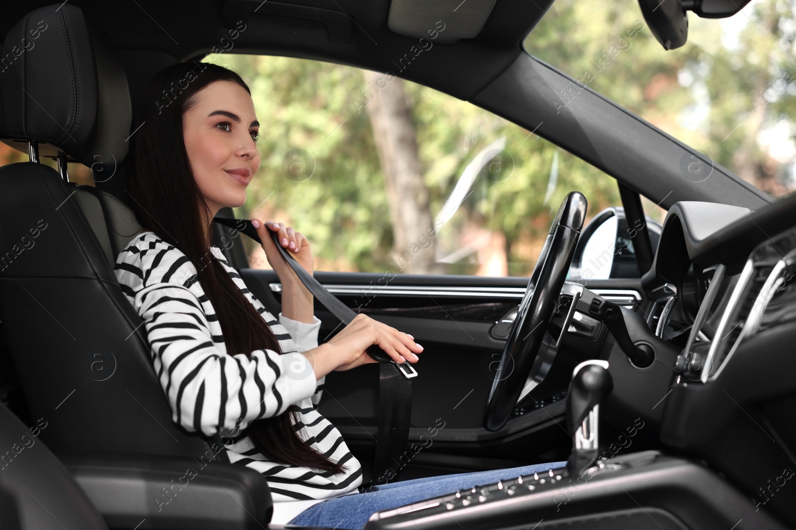 Photo of Woman fastening safety seat belt inside modern car