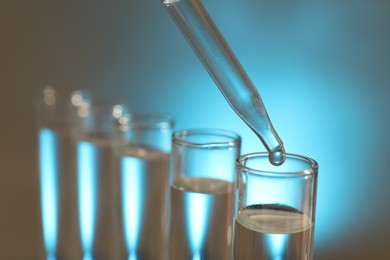 Dripping liquid from pipette into test tube on light background, closeup