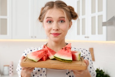 Photo of Beautiful teenage girl with slices of watermelon in kitchen