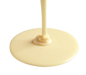 Tasty pouring condensed milk on white background. Dairy product