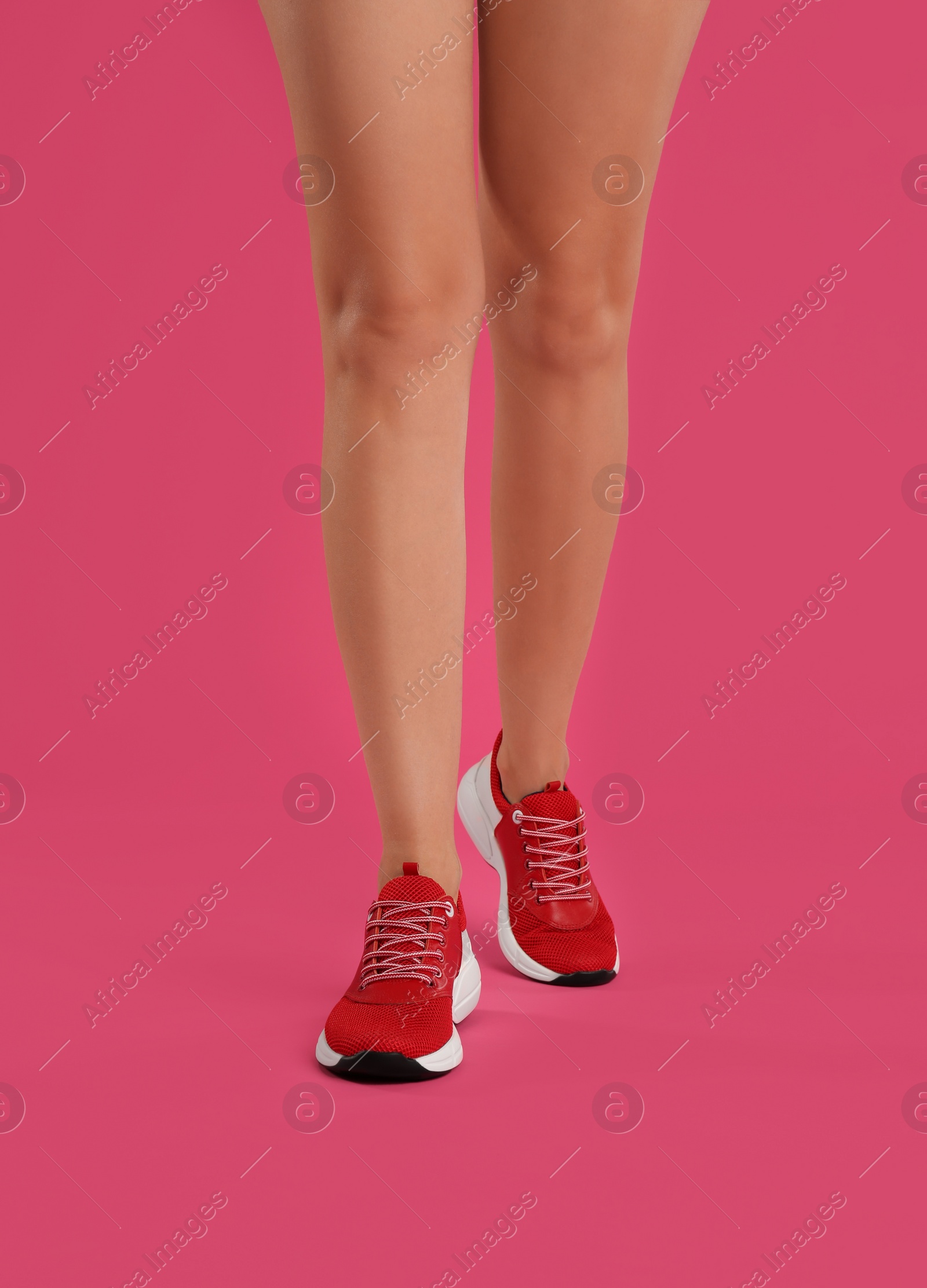 Photo of Woman wearing sneakers on pink background, closeup