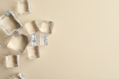 Photo of Crystal clear ice cubes on beige background, flat lay. Space for text