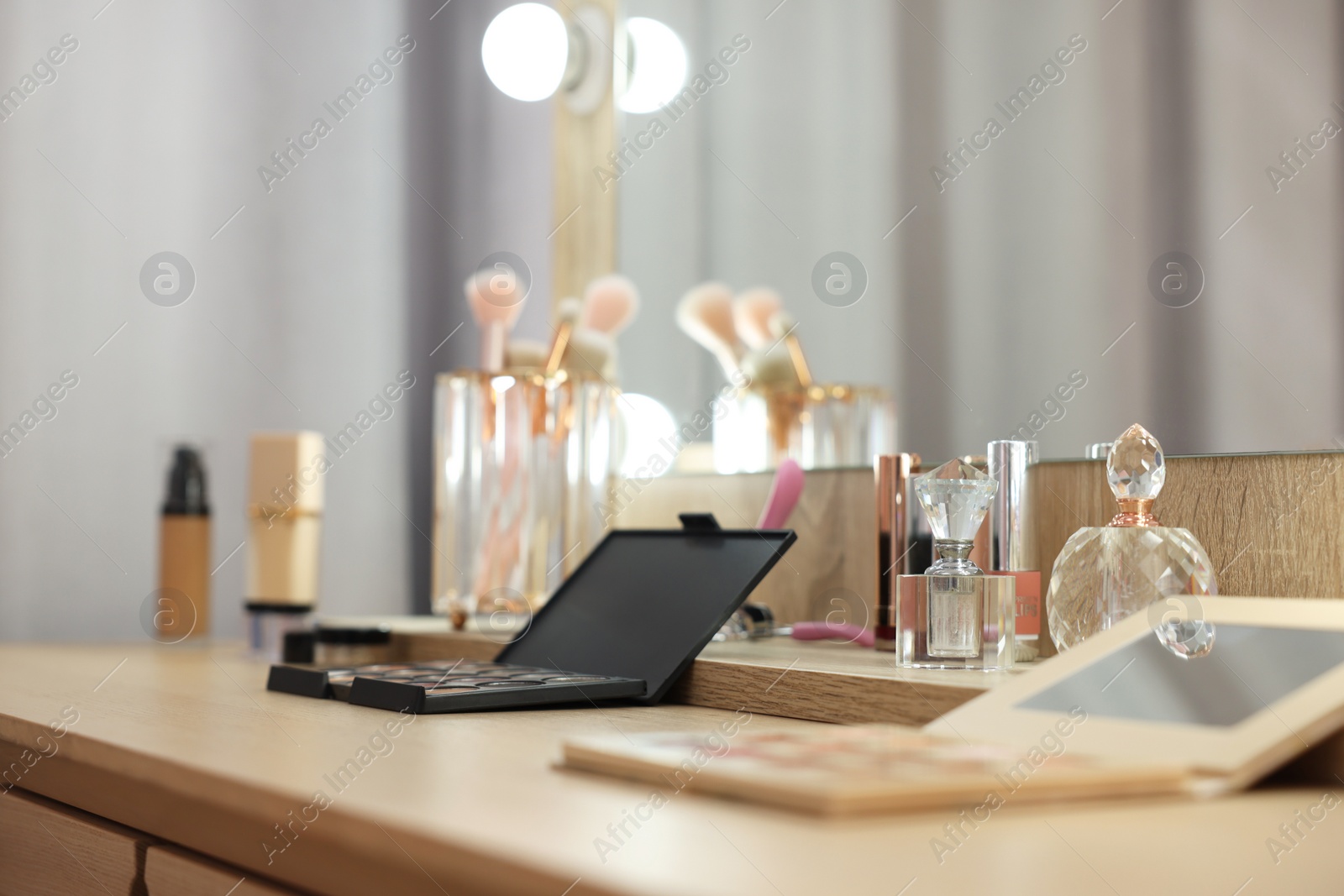 Photo of Cosmetic products and perfumes on wooden dressing table in makeup room