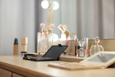 Cosmetic products and perfumes on wooden dressing table in makeup room