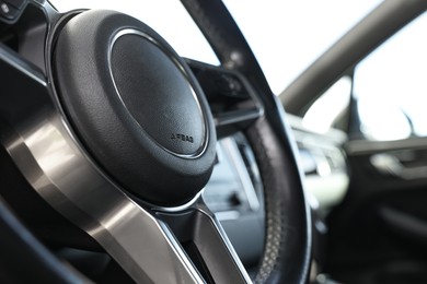 Steering wheel inside of black modern car, closeup
