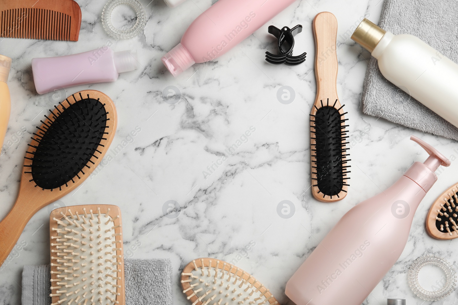 Photo of Flat lay composition with hair cosmetic products and tools on marble background. Space for text