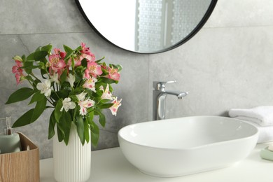 Vase with beautiful Alstroemeria flowers near sink in bathroom