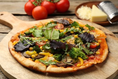 Photo of Delicious vegetarian pizza and ingredients on wooden table, closeup