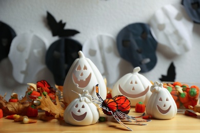 Composition with pumpkin shaped candle holders on wooden table, closeup. Halloween decoration